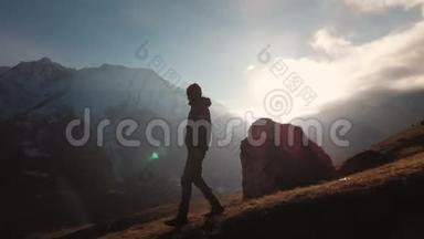 在美丽的日落中，一个人在山的边缘行走的史诗般的照片的鸟瞰。 剪影